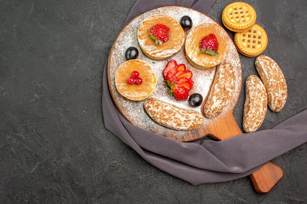 Vista dall'alto gustose frittelle con frutta e torte dolci al buio