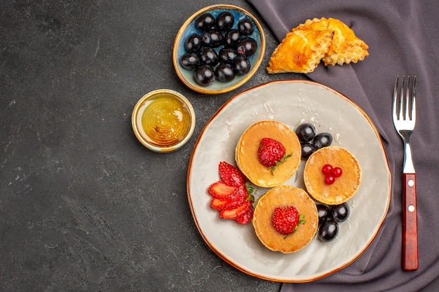 Vista dall'alto gustose frittelle con olive e frutta al buio