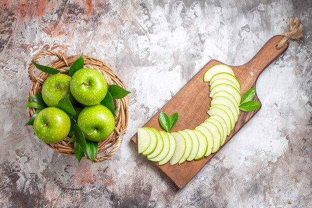Vista dall'alto gustose mele verdi con frutta a fette su sfondo chiaro