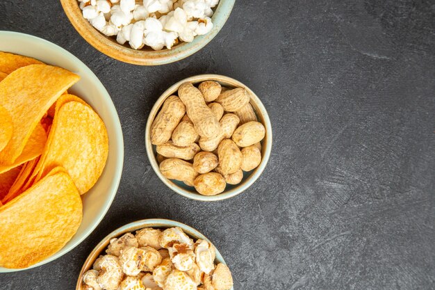 Vista dall'alto gustose patatine al formaggio con diversi snack sullo sfondo scuro