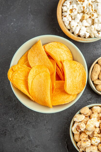 Vista dall'alto gustose patatine al formaggio con diversi snack sullo sfondo scuro