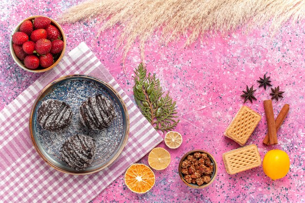 Vista dall'alto gustose torte al cioccolato con fragole rosse fresche sul rosa