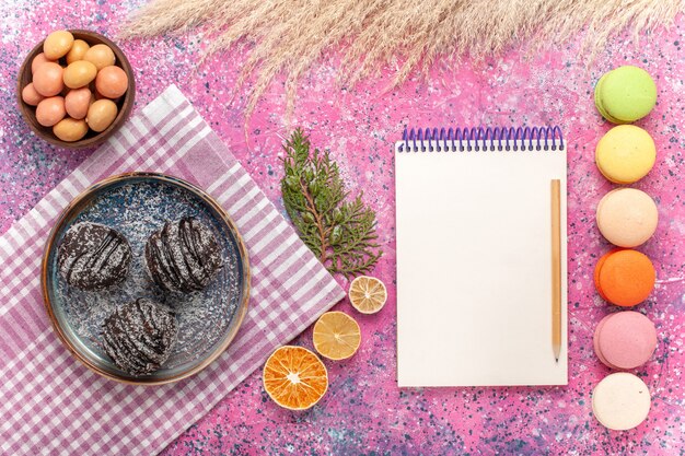 Vista dall'alto gustose torte al cioccolato con macarons sul rosa