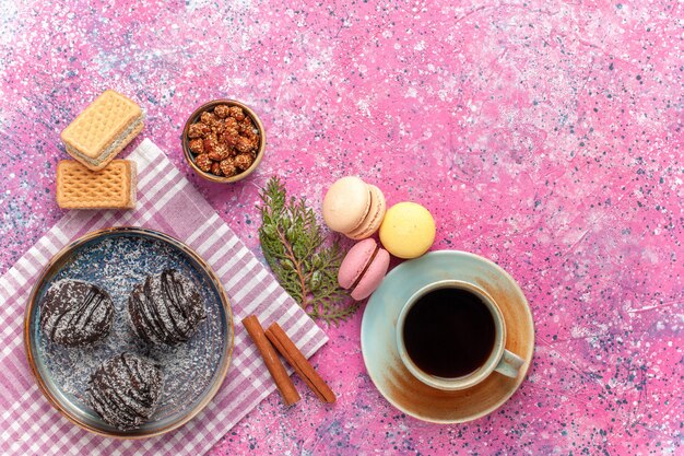 Vista dall'alto gustose torte al cioccolato con tè e macarons sul rosa