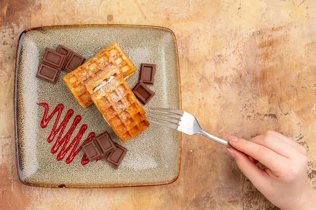 Vista dall'alto gustose torte waffle con barrette di cioccolato sulla scrivania marrone