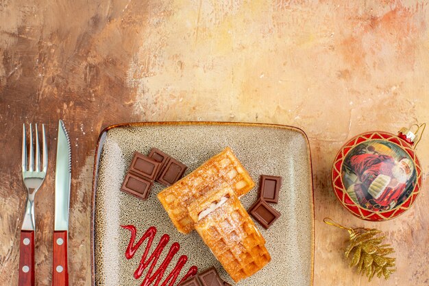 Vista dall'alto gustose torte waffle con barrette di cioccolato sulla scrivania marrone