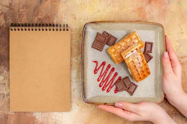 Vista dall'alto gustose torte waffle con barrette di cioccolato sullo sfondo marrone