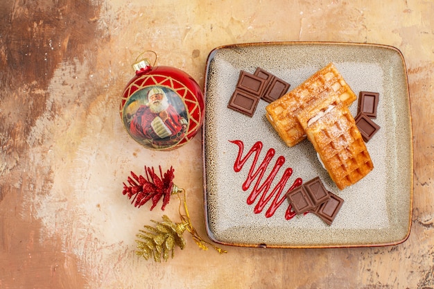 Vista dall'alto gustose torte waffle con barrette di cioccolato sullo sfondo marrone