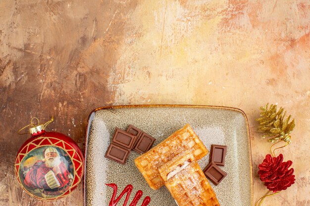 Vista dall'alto gustose torte waffle con barrette di cioccolato sullo sfondo marrone