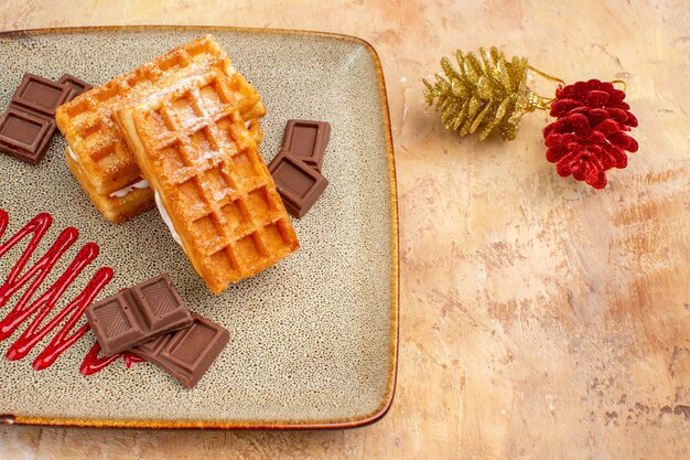 Vista dall'alto gustose torte waffle con barrette di cioccolato sullo sfondo marrone