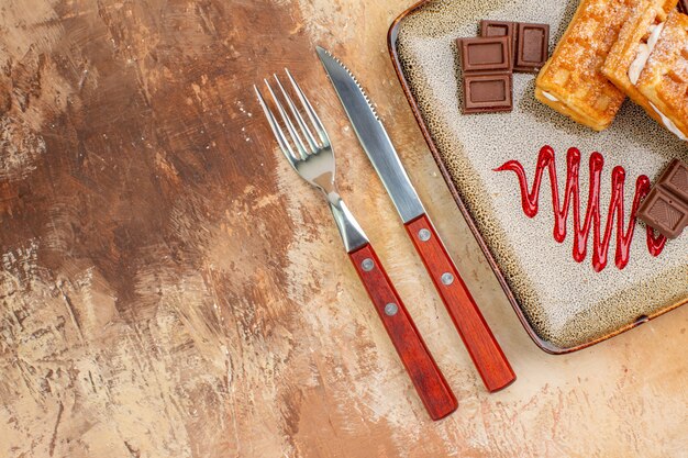 Vista dall'alto gustose torte waffle con barrette di cioccolato sullo sfondo marrone