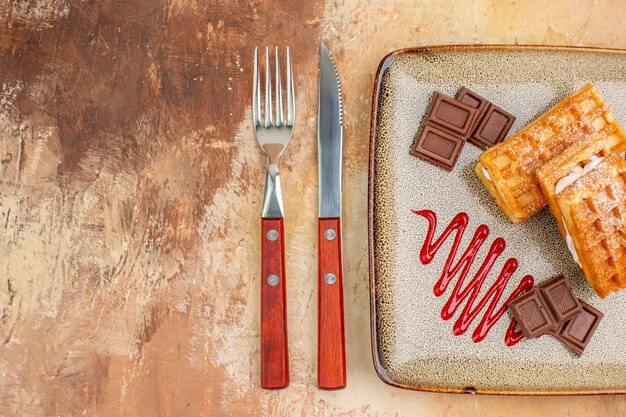 Vista dall'alto gustose torte waffle con barrette di cioccolato sullo sfondo marrone