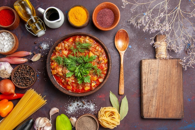 Vista dall'alto gustose verdure cotte affettate con salsa e condimenti su una superficie scura zuppa di salsa di cibo per la cena
