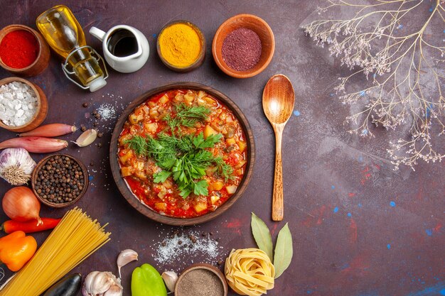 Vista dall'alto gustose verdure cotte affettate con salsa e condimenti sul pasto cena cibo zuppa di sfondo scuro