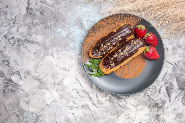 Vista dall'alto gustosi bignè al cioccolato con fragole sul biscotto da dessert leggero