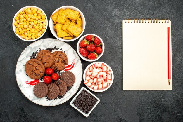 Vista dall'alto gustosi biscotti al cioccolato con diversi snack su sfondo scuro biscotti dolci