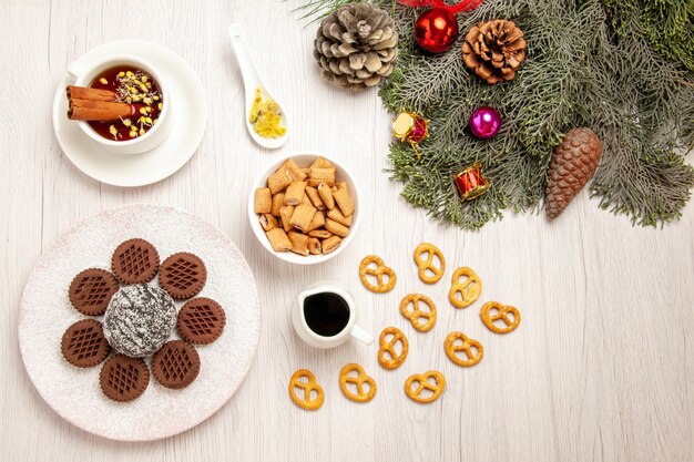 Vista dall'alto gustosi biscotti al cioccolato con poca torta al cacao e tè su bianco