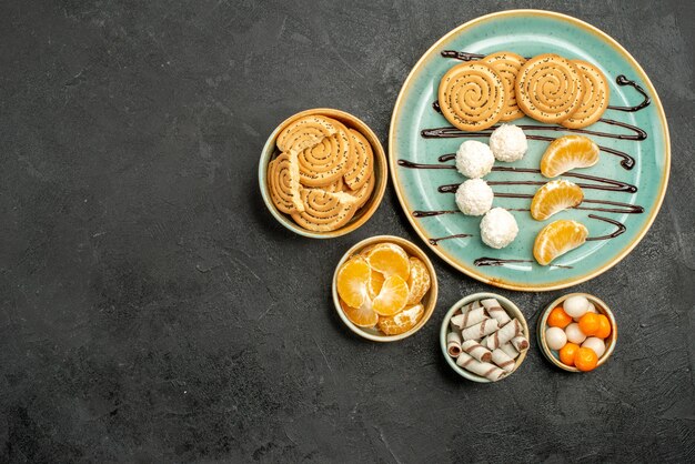 Vista dall'alto gustosi biscotti di zucchero con caramelle su sfondo grigio scuro