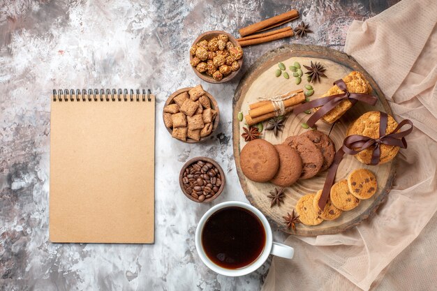 Vista dall'alto gustosi biscotti dolci con una tazza di caffè sul tavolo luminoso