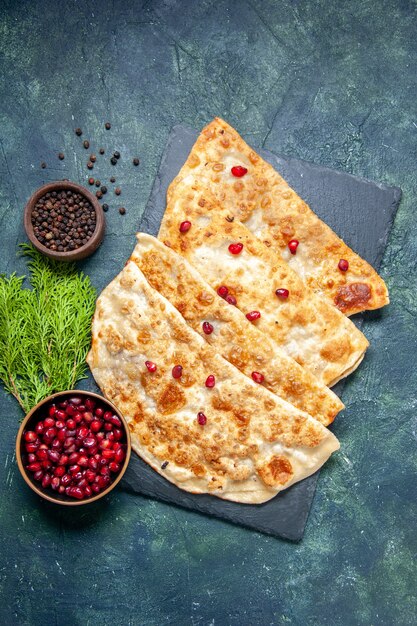 Vista dall'alto gustosi gutabs sottili hotcakes con carne e melograni su sfondo scuro torta di pasticceria torta di pasta colorata pasta da forno