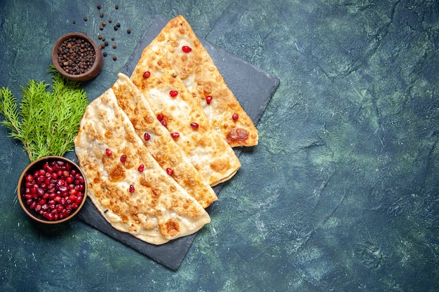 Vista dall'alto gustosi gutabs sottili hotcakes con carne e melograni su sfondo scuro torta di pasticceria torta di pasta colorata pasta da forno