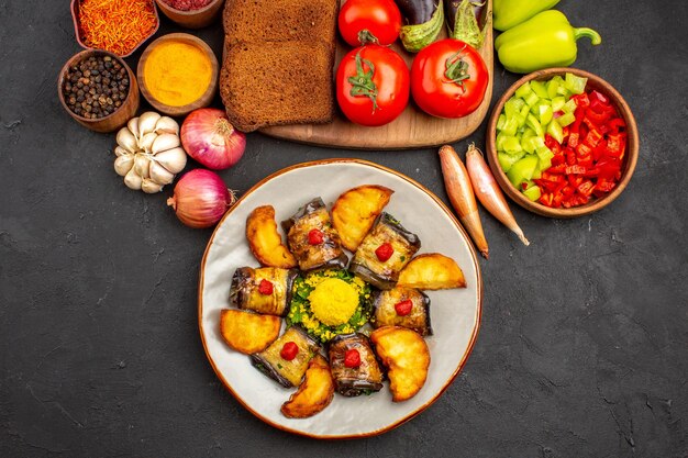 Vista dall'alto gustosi involtini di melanzane con patate pagnotte di pane scuro e verdure su piatto di superficie scura salute insalata pasto cibo