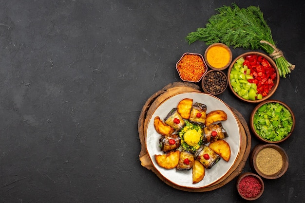 Vista dall'alto gustosi involtini di melanzane piatto cucinato con patate e condimenti diversi su superficie scura pasto per piatti cena cibo