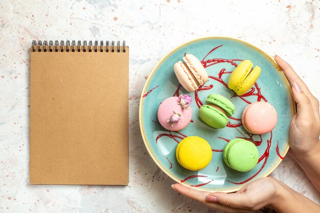 Vista dall'alto gustosi macarons francesi all'interno del piatto su dolci di biscotti con torta bianca