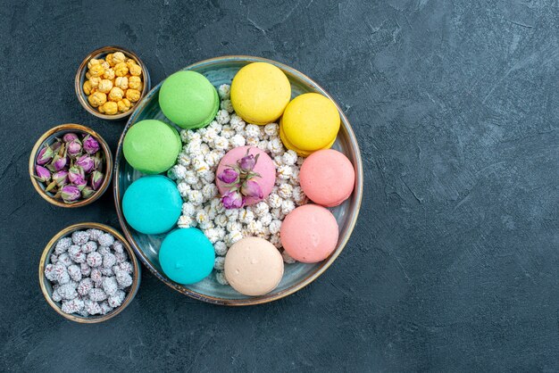 Vista dall'alto gustosi macarons francesi con caramelle su grigio