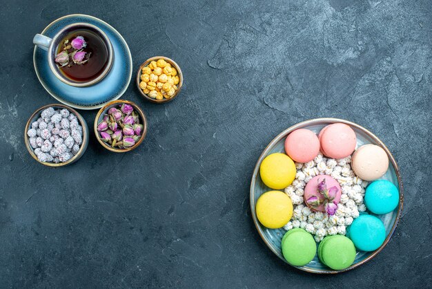 Vista dall'alto gustosi macarons francesi con una tazza di tè su oscurità