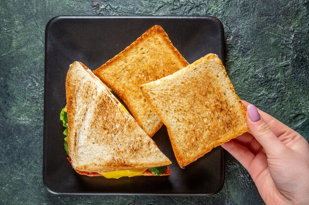 Vista dall'alto gustosi panini al prosciutto con toast all'interno della piastra sulla superficie scura