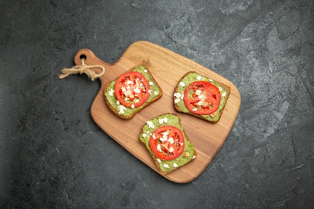 Vista dall'alto gustosi panini di avocado con pomodori rossi a fette sullo sfondo grigio panino hamburger pane panino spuntino