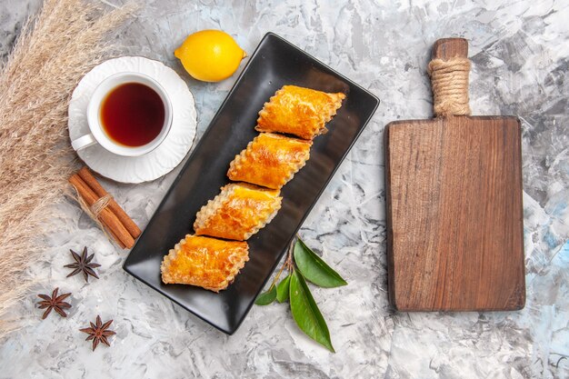 Vista dall'alto gustosi pasticcini dolci con tè su torta di pasticceria dolce bianca chiara