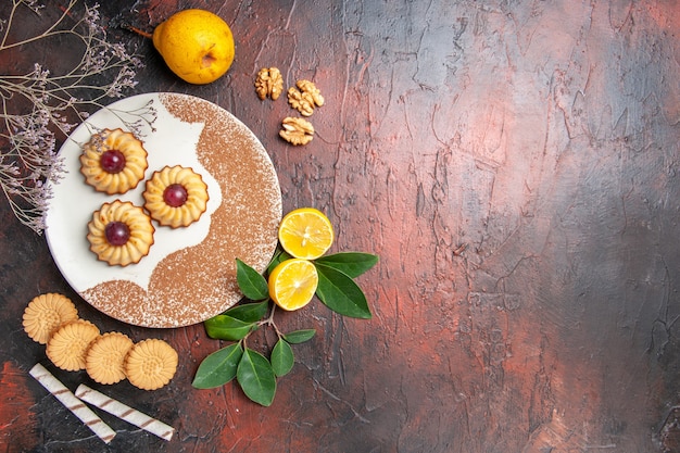 Vista dall'alto gustosi piccoli biscotti con frutta sul biscotto dolce torta di zucchero da tavola scuro