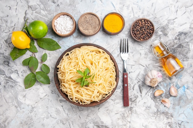 Vista dall'alto gustosi spaghetti con condimenti su un piatto di pasta bianca da scrivania