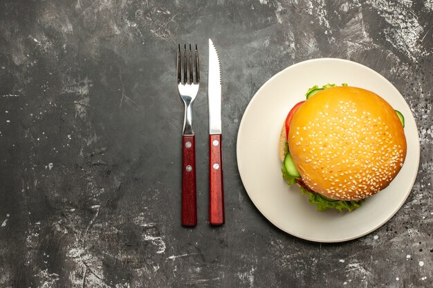 Vista dall'alto gustoso hamburger di carne con verdure sul panino panino superficie scura fast-food