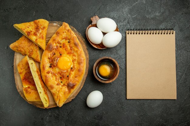 Vista dall'alto gustoso pane all'uovo cotto a fette con uova fresche sullo sfondo grigio pane panino pasta cibo colazione