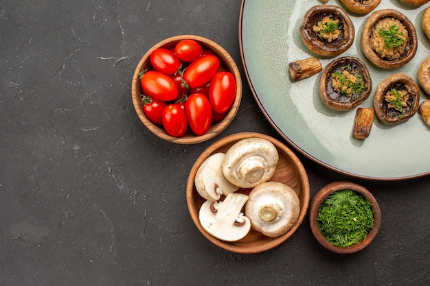 Vista dall'alto gustoso pasto di funghi con pomodori freschi e verdure su un piatto di superficie scura cena che cucina funghi
