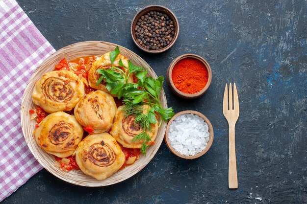 Vista dall'alto gustoso pasto di pasta con carne all'interno del piatto insieme a condimenti sulla verdura di carne di farina di cibo scuro scrivania