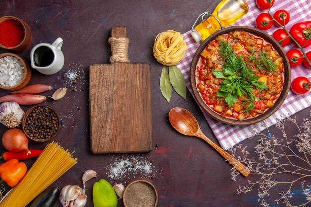 Vista dall'alto gustoso pasto di salsa di verdure cotte con pomodori e condimenti su sfondo scuro