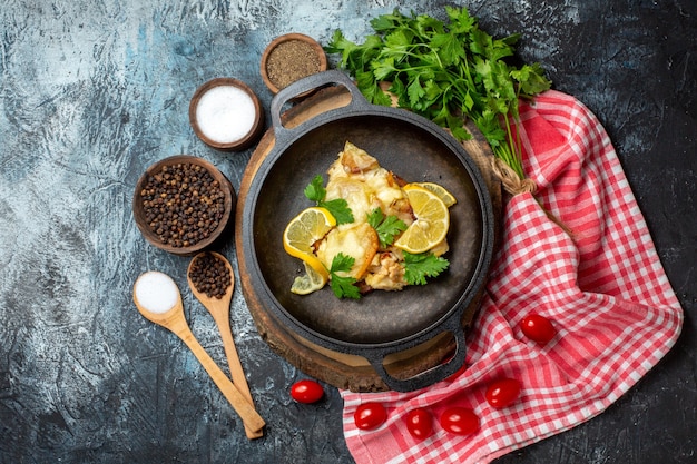 Vista dall'alto gustoso pesce fritto con limone e prezzemolo in padella su tavola di legno