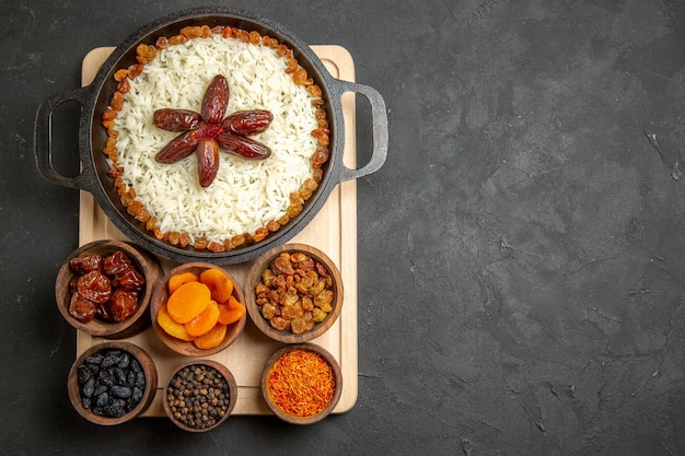 Vista dall'alto gustoso piatto di riso cotto plov con diverse uvette fresche su sfondo scuro piatto di uvetta riso cena olio cibo