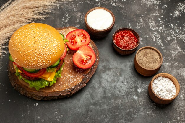 Vista dall'alto hamburger di carne di formaggio con condimenti sulle patatine fritte di carne panino panino superficie scura