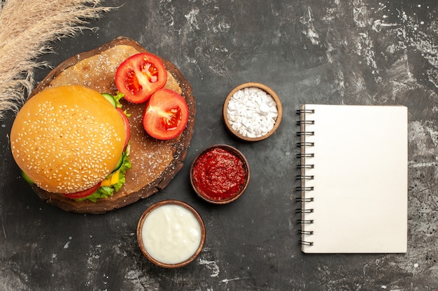 Vista dall'alto hamburger di carne di formaggio con condimenti sulle patatine fritte panino panino di carne superficie scura