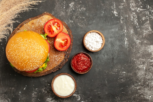 Vista dall'alto hamburger di carne di formaggio con condimenti sulle patatine fritte panino panino di carne superficie scura