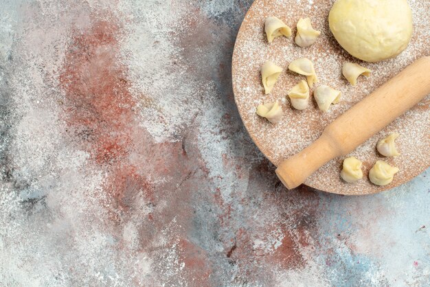 Vista dall'alto il mattarello della pasta dushbara sulla spianatoia sulla superficie nuda con lo spazio della copia