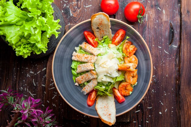 Vista dall'alto Insalata caesar con petto di pollo e gamberi alla griglia, gamberi, pomodori, insalata fresca in un piatto