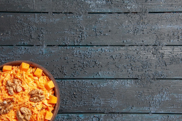 Vista dall'alto insalata di carote fresche grattugiate con noci e aglio su scrivania scura dieta salute insalata di colore maturo