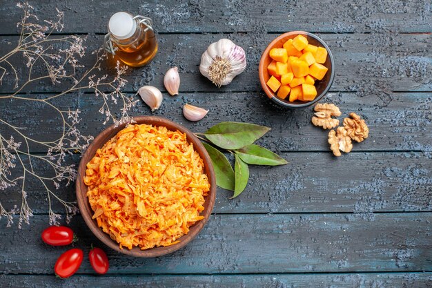 Vista dall'alto insalata di carote grattugiate con noci e aglio sullo sfondo scuro dieta salutare insalata matura di colore arancione