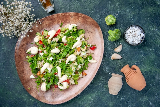 vista dall'alto insalata di verdure all'interno di un piatto elegante con posate su sfondo blu scuro colore salute pranzo ristorante cucina dietetica